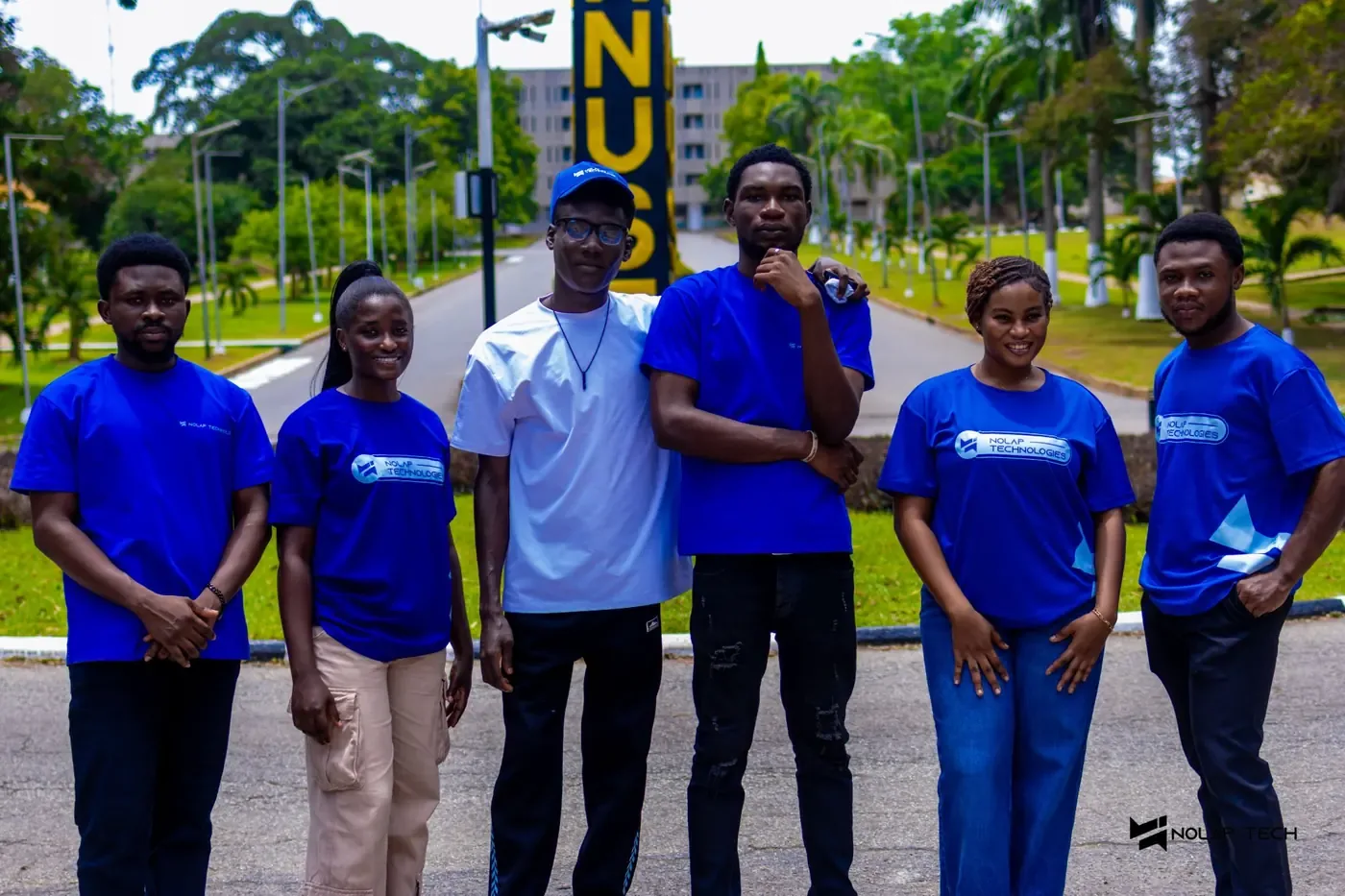 Six NOLAP team members in blue shirts standing together on the KNUST campus